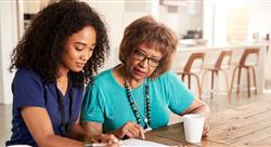 Female healthcare worker filling in a form with a senior woman during a home health visit